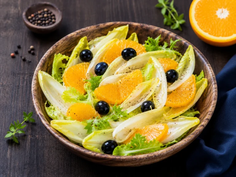 Salade d’endives fraîches avec oranges en quartiers et olives noires dans un bol rustique